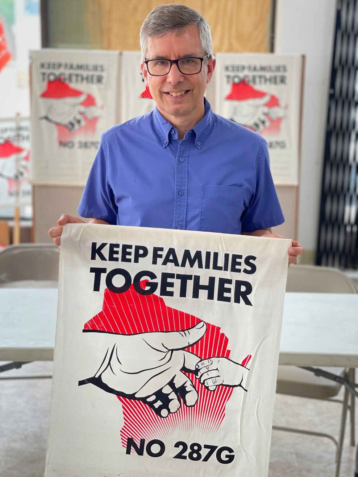 Staff Attorney Tim Muth holding a "Keep families together, no 287g" banner